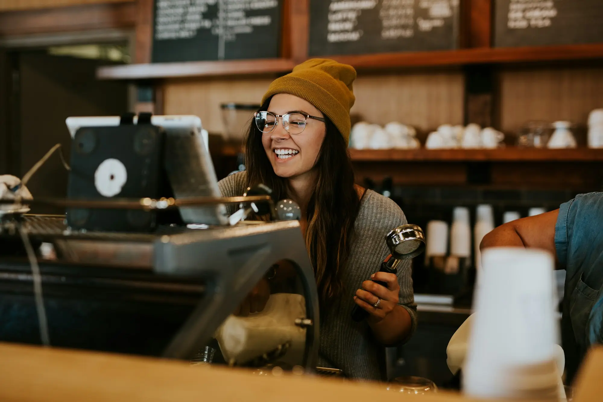 Cafe owner smiling behind her coffee counter