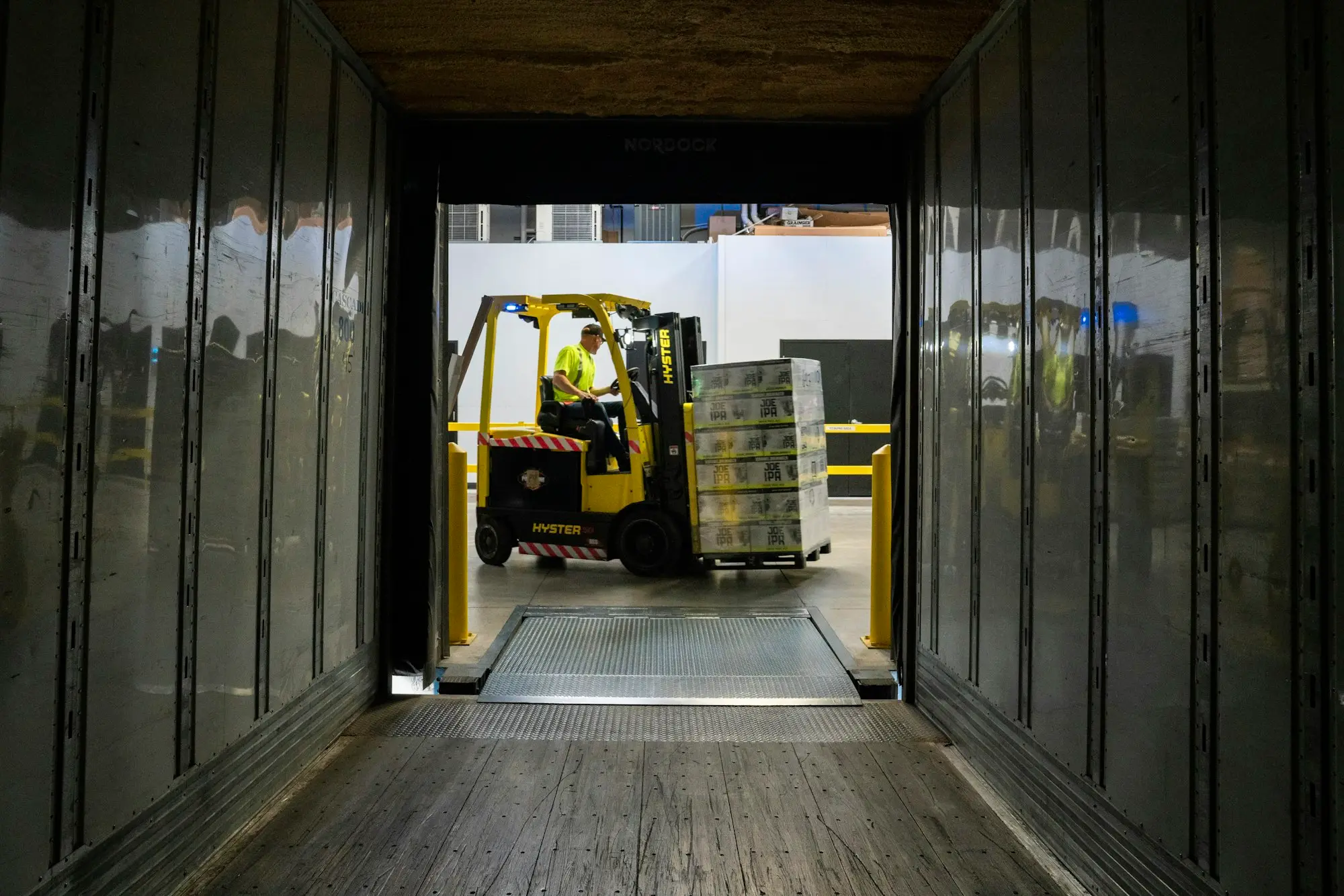 Forklift unloading stock from a container into a warehouse